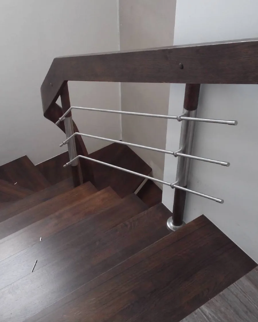 Narożnik balustrady przy ostatnich stopniach, drewniany pochwyt i poziome rurki stalowe — Dynów