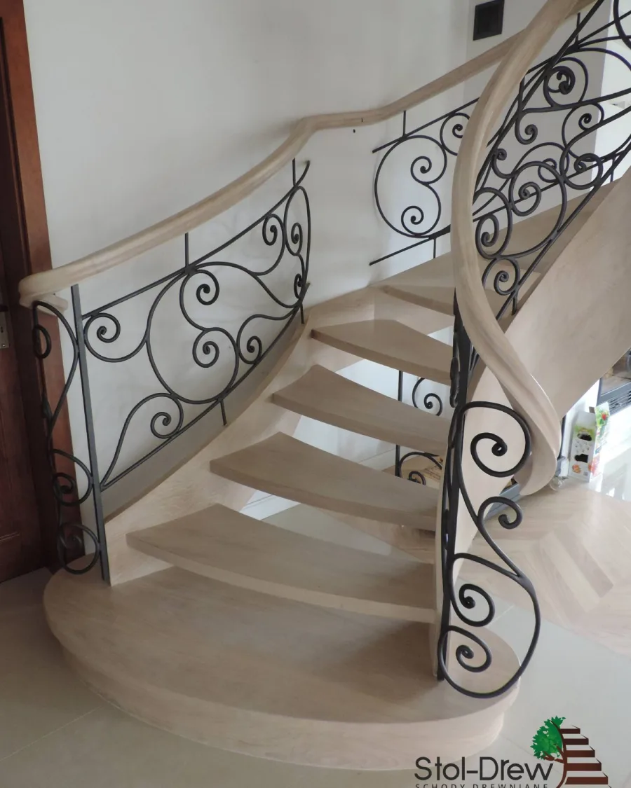 Dębowe schody samonośne gięte, zabielone, z kutą balustradą w ozdobne woluty, widok od dołu — Krosno