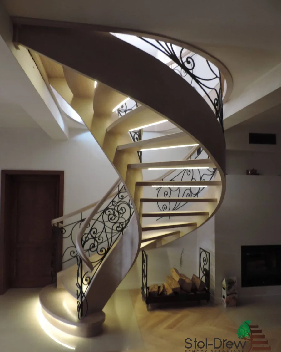 Spiralny bieg schodów od dołu, z podświetlonymi stopniami i kutą balustradą na górze — Krosno