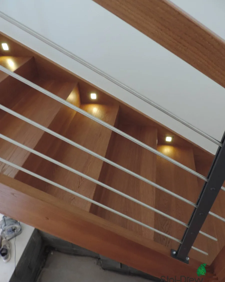 Zbliżenie na stopnie z wbudowanymi w wangę lampkami LED i rurkę balustrady od góry — Przemyśl