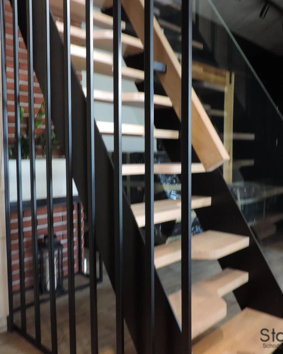 Zbliżenie na dębowe stopnie, czarne pionowe pręty i szybę balustrady przy biegu — Przemyśl