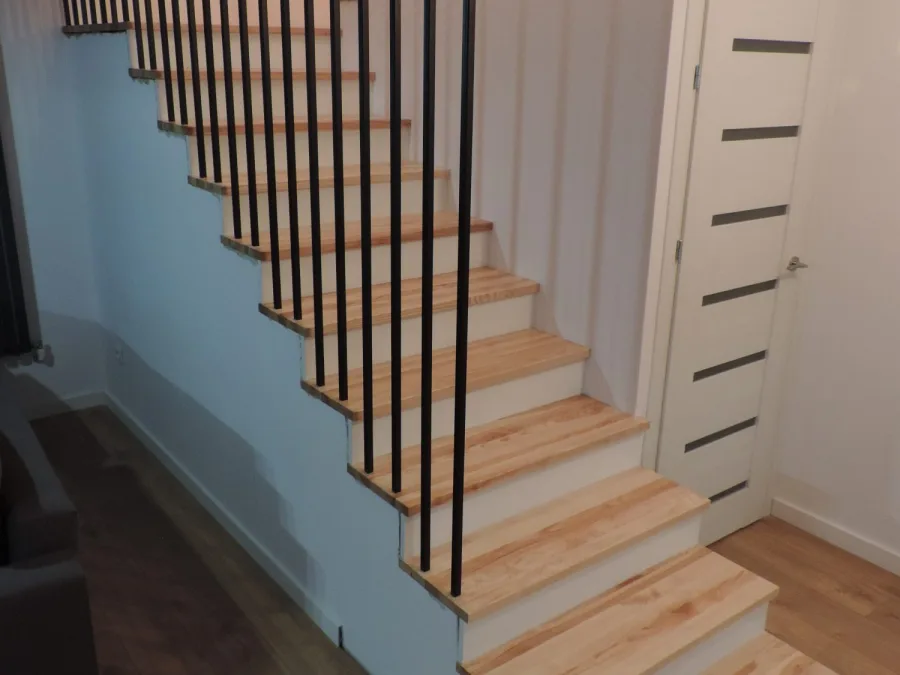 Schody z jesionu z czarną balustradą z profili