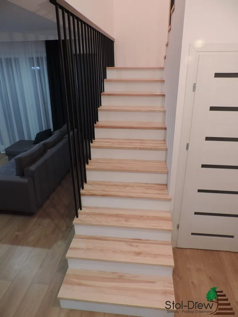 Jesionowe schody na beton z białymi podstopniami i czarną balustradą z pionowych prętów — Dukla