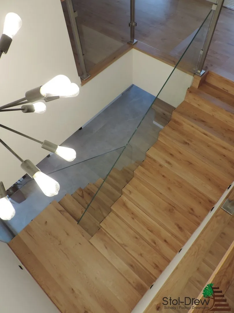 Szklana balustrada pod światłem lamp żarówkowych, stopnie z dębu w stylu dywanowym od góry — Przeworsk