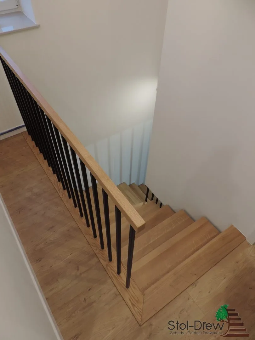 Widok z góry na dolny bieg, drewniany pochwyt i czarne pręty balustrady — Iwonicz-Zdrój