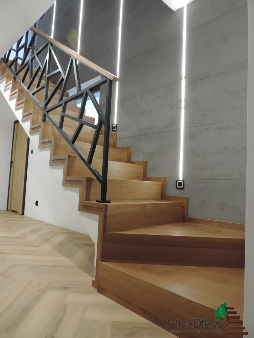 Dębowe zabiegi schodów dywanowych w dolnej części biegu, obok ściana z betonu architektonicznego — Zagórz