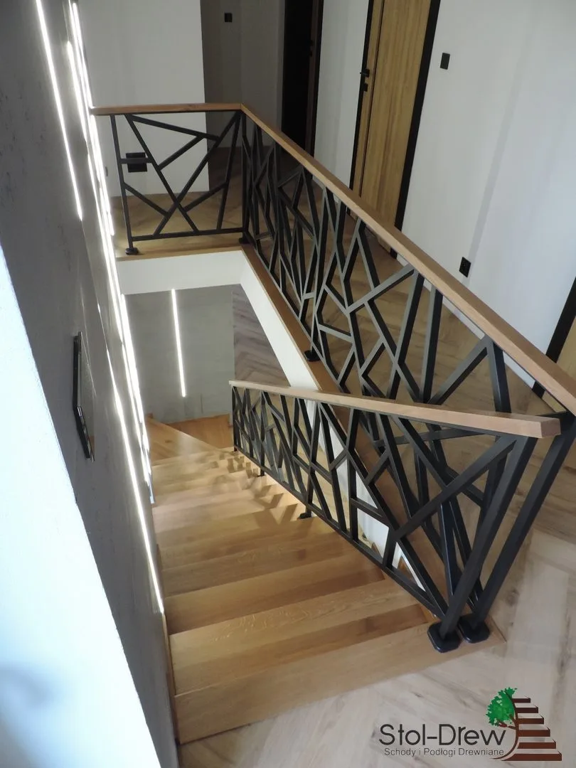 Balustrada z czarnych profili stalowych o geometrycznym wzorze, widok z piętra wzdłuż biegu — Zagórz