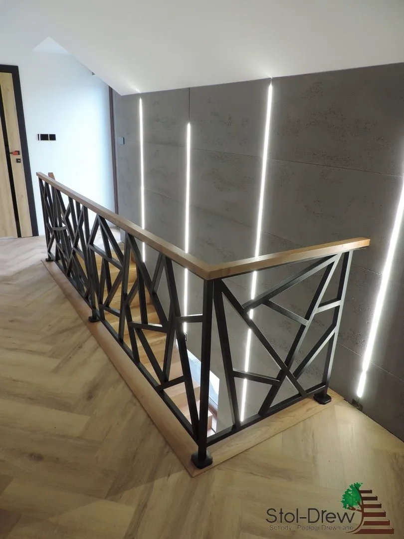 Narożnik balustrady z czarnej stali i dębowy pochwyt, w tle ściana z oświetleniem liniowym — Zagórz