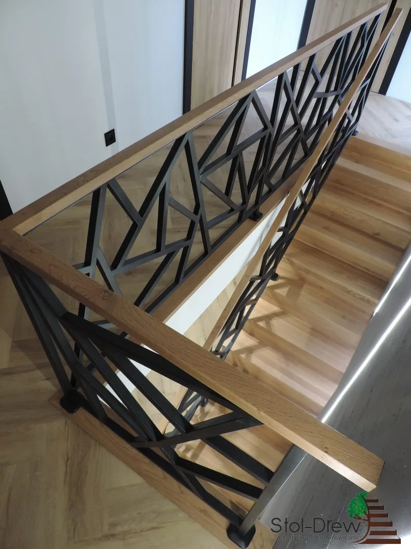 Dębowy pochwyt balustrady i czarne profile stalowe, ujęcie z góry na schody dywanowe — Zagórz