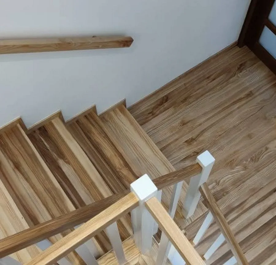 Widok z góry na zabiegi dębowych schodów na beton i biały słupek balustrady z tralkami — Rzeszów