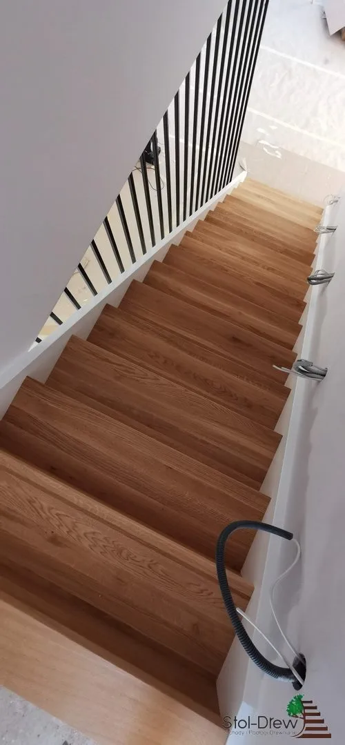 Widok z góry w dół na dębowe stopnie i czarne pionowe pręty balustrady — Krosno